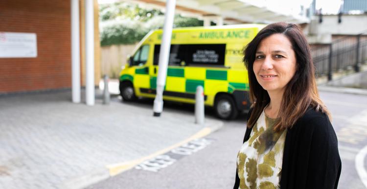 woman smiling at the camera in front of an ambulance