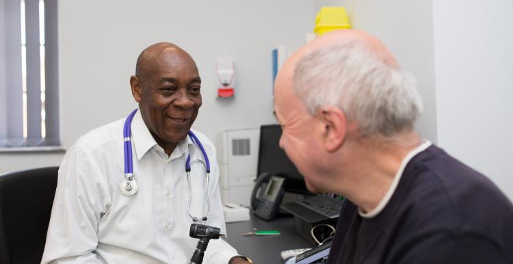 GP sitting opposite a patient about to take their temperature