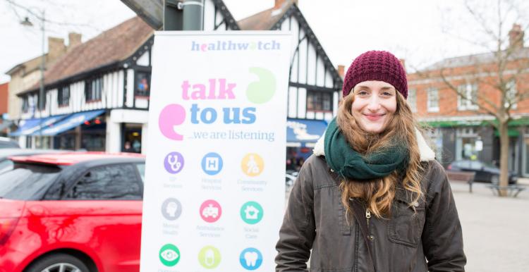 Woman standing outside, in front of a Healthwatch banner