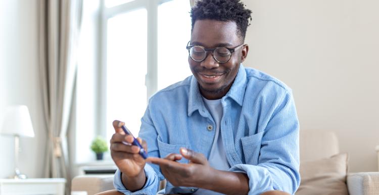 Man pricking his finger to check glucose levels in blood.
