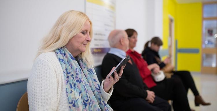 A woman sitting in a waiting room looking at her phone