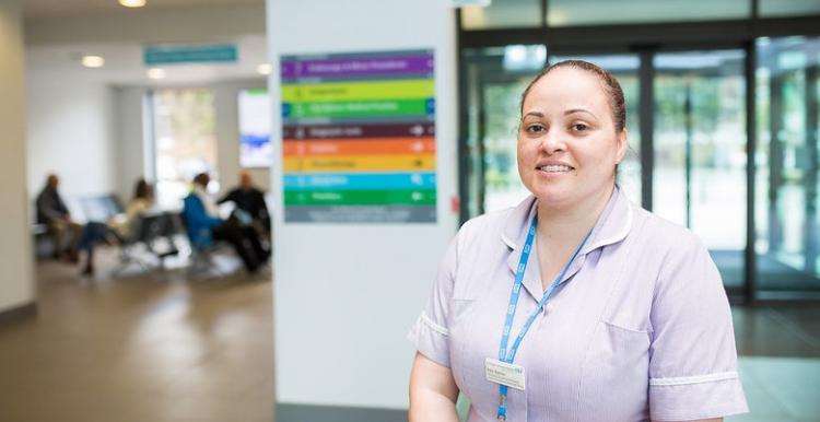 A healthcare assistant standing in the hospital entrance