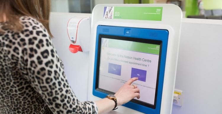 A lady touching an appointment screen in a hospital