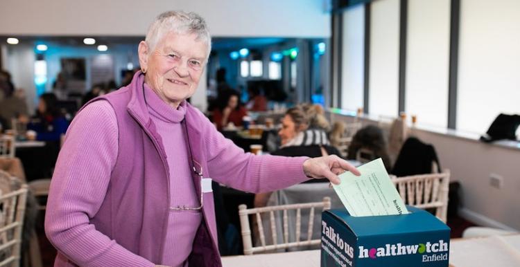 A lady putting a piece of paper in a box