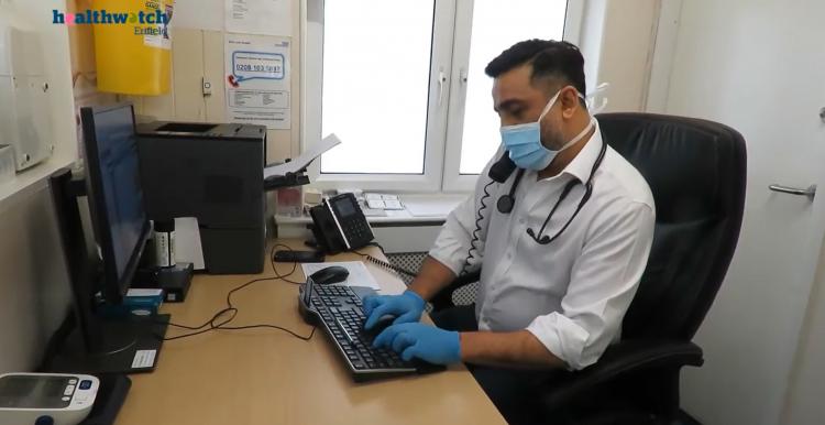 Image of GP at his desk on the phone and typing on his computer simultaneously