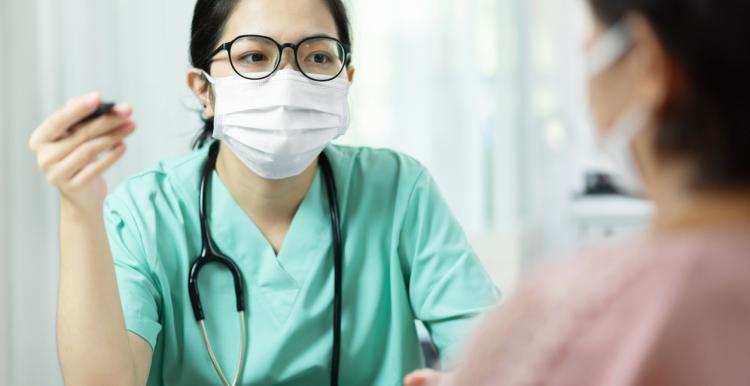 female doctor wearing mask seeing patient