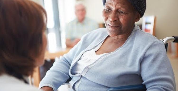 Black elderly woman in a nursing home being spoken to by a nurse