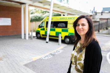 woman smiling at the camera in front of an ambulance