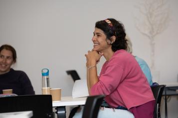 Woman smiling, watching workshop. 