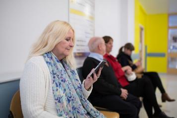 A woman sitting in a waiting room looking at her phone