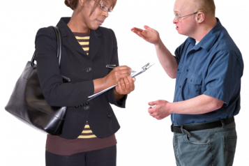 Image of a man making a complaint to a lady who is holding a clip board and writing notes