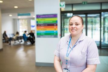 A healthcare assistant standing in the hospital entrance