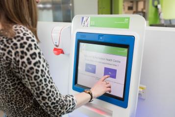 A lady touching an appointment screen in a hospital