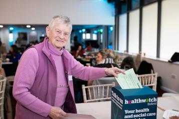 A lady putting a piece of paper in a box