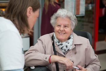 A young lady talking to an older lady sitting in a chair