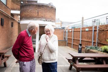 Two elderly people standing outside talking