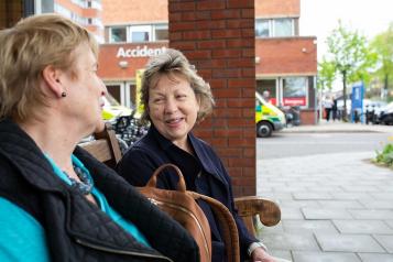 Two ladies sitting outside a hospital on a bench