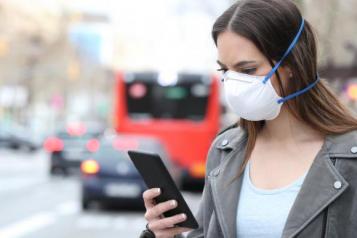 female wearing mask holding phone