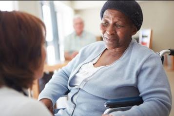 Black elderly woman in a nursing home being spoken to by a nurse