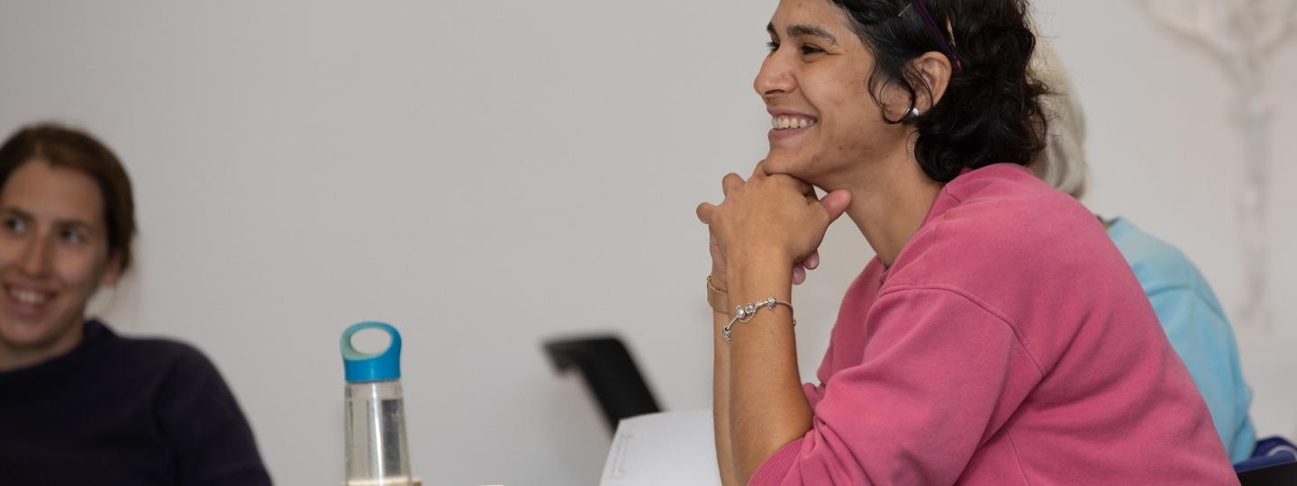 Woman smiling, watching workshop. 